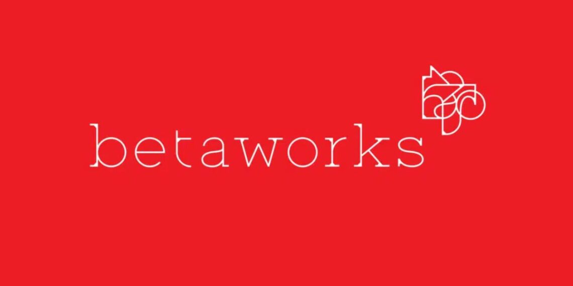 A dynamic workspace with startup founders collaborating at Betaworks Accelerator, featuring laptops, brainstorming sessions, and a modern office environment.