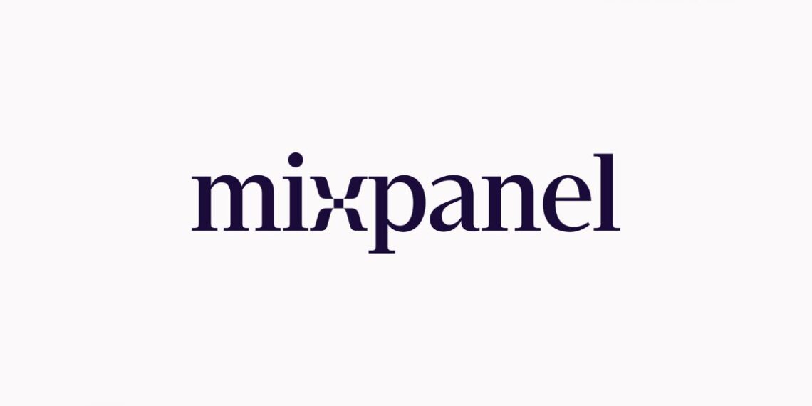 A digital illustration showing the MixPanel logo alongside a laptop screen displaying an analytics dashboard with charts, graphs, and user behavior metrics. In the background, a startup team is collaborating, discussing data insights, and strategizing based on performance trends.