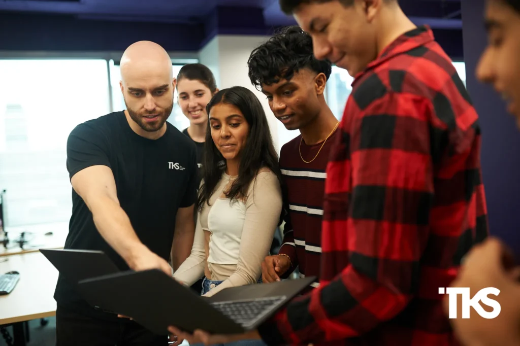 get into HF0 program session with a mentor guiding a group of students reviewing work on laptops