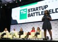 A startup founder pitching on stage at TechCrunch Startup Battlefield in front of a panel of investors and a live audience.