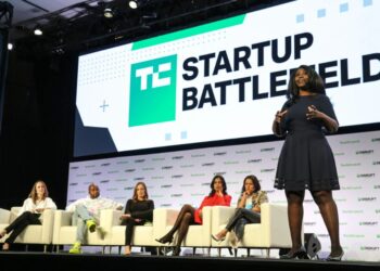 A startup founder pitching on stage at TechCrunch Startup Battlefield in front of a panel of investors and a live audience.
