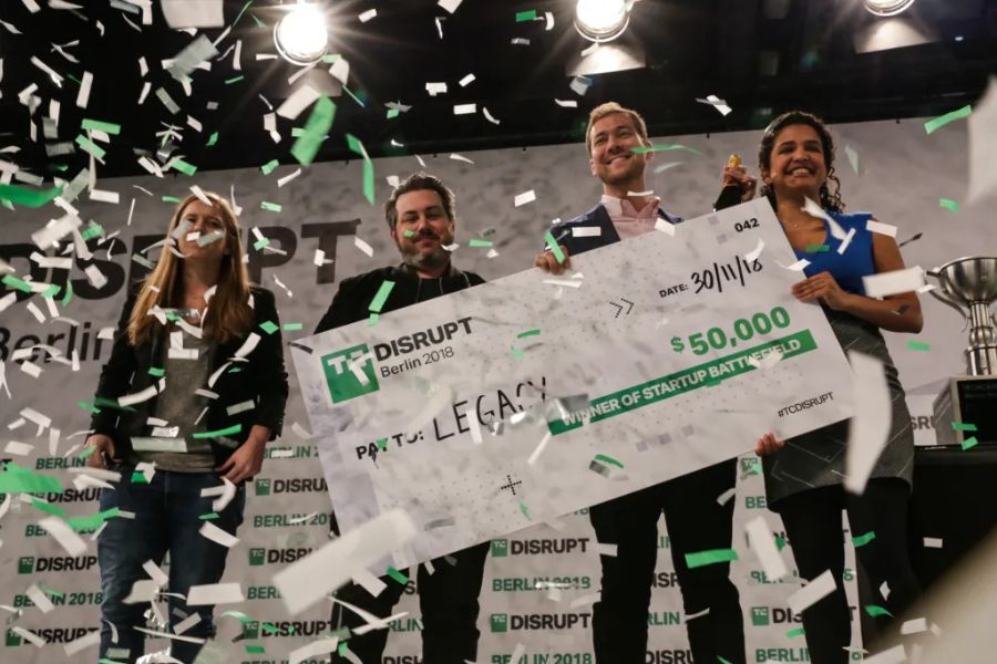 Startup founders celebrating on stage after winning TechCrunch Startup Battlefield, holding the Disrupt Cup.