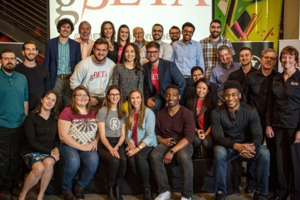 A group photo of the gBETA accelerator team smiling together in a modern workspace.