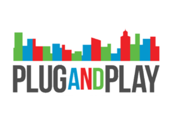 Founders networking at Plug and Play Tech Center with banners showcasing corporate innovation and startup logos.