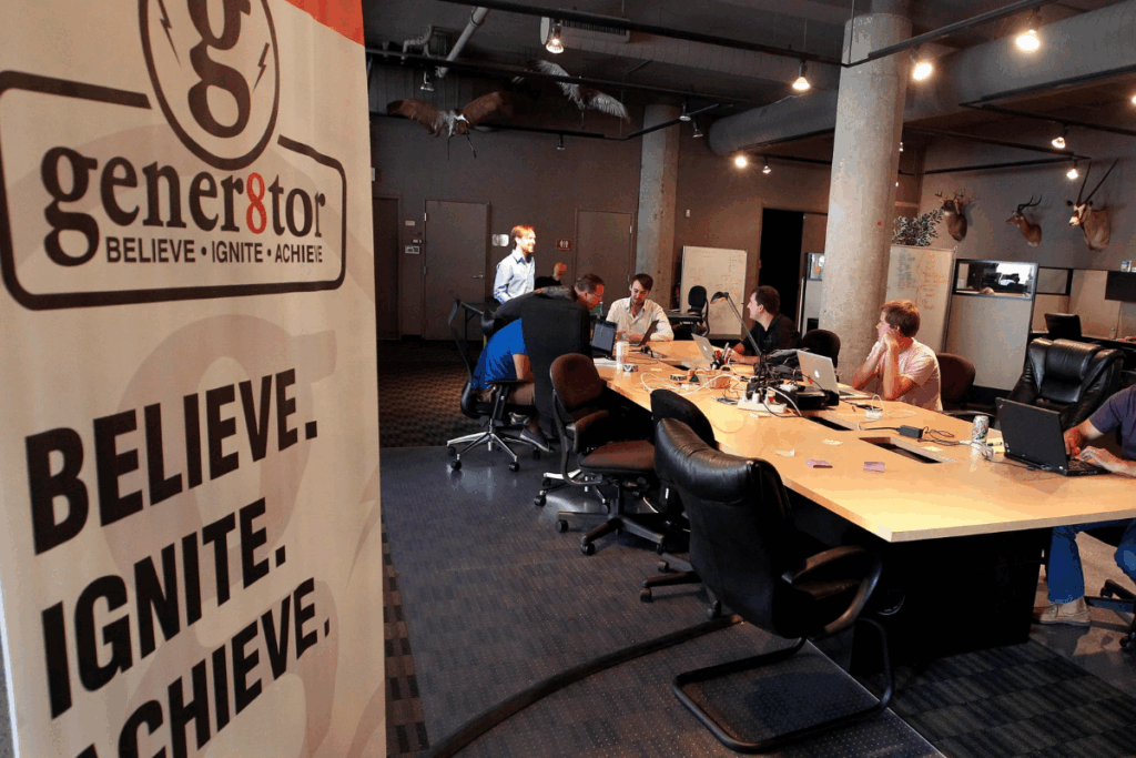 A vibrant scene from a gener8tor accelerator event showing founders networking, pitching, and engaging with mentors in a dynamic setting.