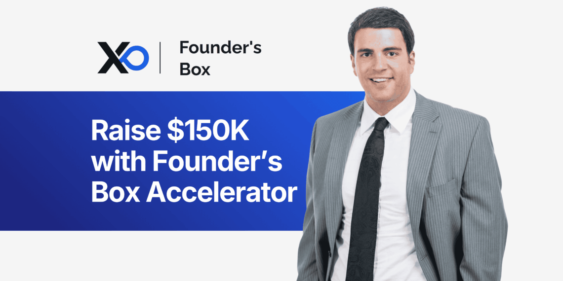 Smiling man in a gray suit standing beside a banner that says “Raise $150K with Founder’s Box Accelerator.”