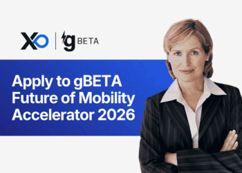 Confident woman in a pinstripe suit stands with folded arms beside a banner inviting founders to apply to the gBETA Future of Mobility Accelerator 2026.