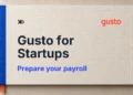 Gusto payroll preparation handbook in ivory with a blue spine and coral bookmark.